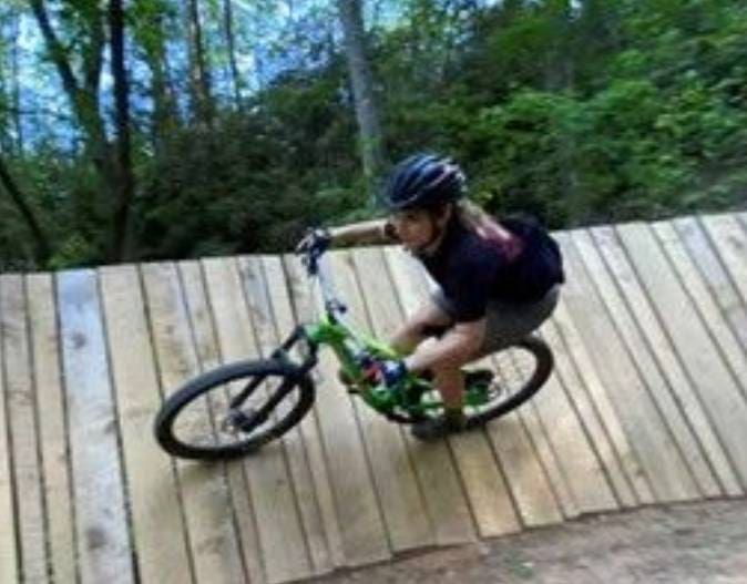 A person riding a bike on top of a wooden ramp.