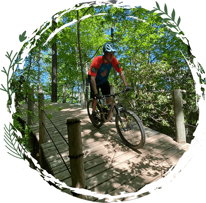 A man riding a bike down the side of a wooden bridge.