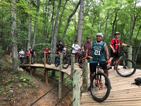 A group of people riding bikes on top of a wooden bridge.
